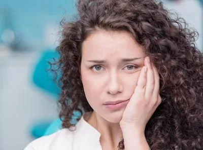 woman holding her mouth due to tooth pain