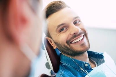 patient smiling while talking with Dr. Tang about his new dental implants